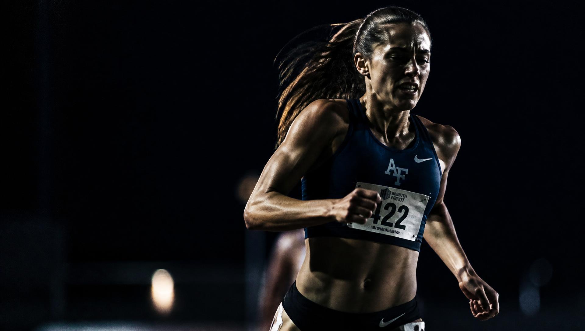 Female athlete competing mid-effort under directional light