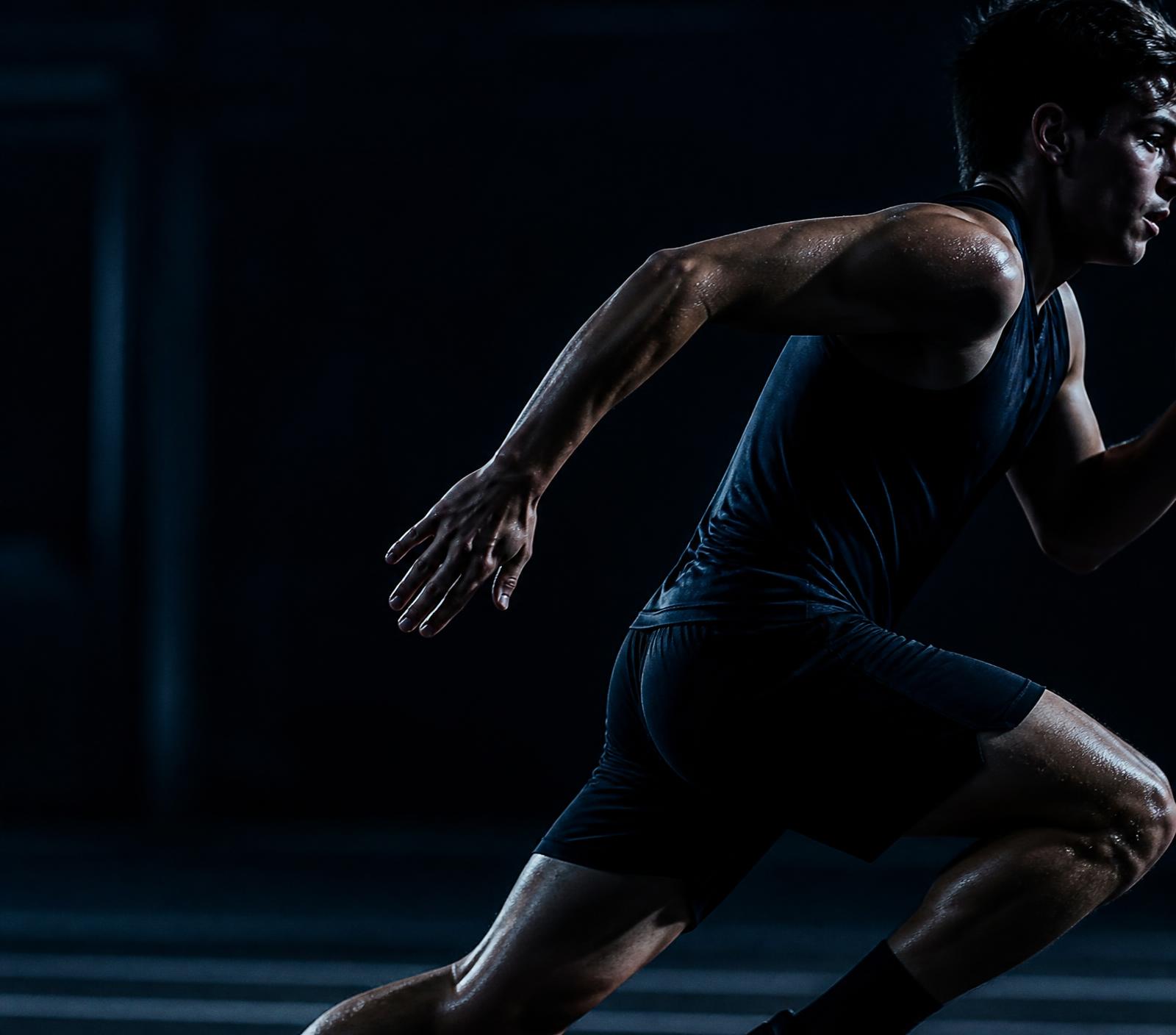 A young athlete mid-stride under stadium light